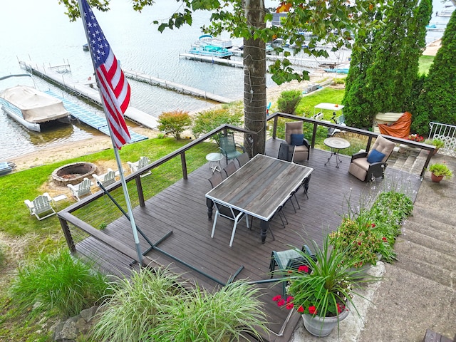 wooden deck with a water view, an outdoor fire pit, and a dock