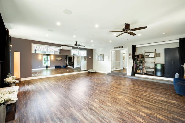 unfurnished living room featuring dark wood-type flooring and ceiling fan