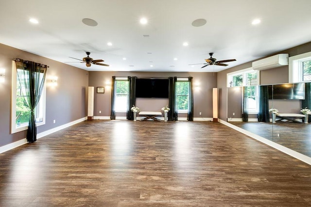 unfurnished living room with ceiling fan, plenty of natural light, dark hardwood / wood-style floors, and an AC wall unit