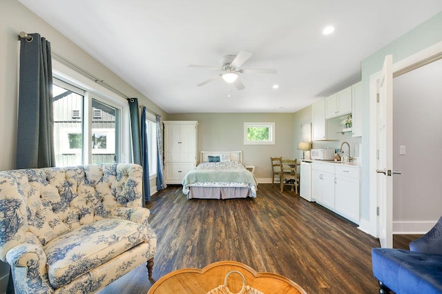 bedroom featuring dark hardwood / wood-style floors, sink, ceiling fan, and multiple windows