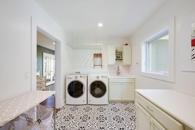 laundry area with sink, cabinets, independent washer and dryer, and a healthy amount of sunlight