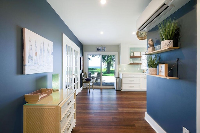 kitchen with french doors, white cabinetry, tasteful backsplash, an AC wall unit, and dark hardwood / wood-style flooring