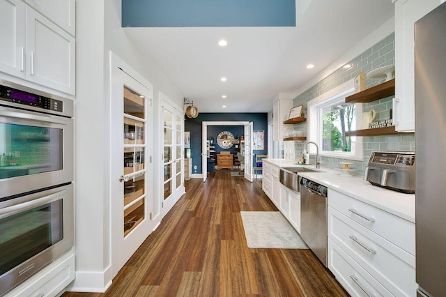 kitchen with tasteful backsplash, appliances with stainless steel finishes, sink, and white cabinets