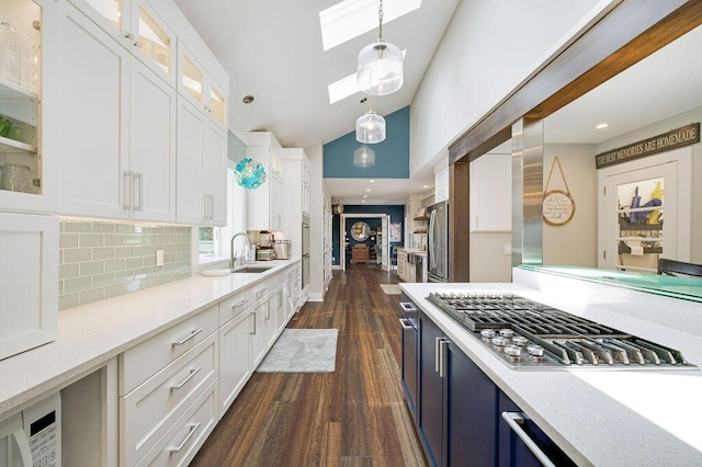 kitchen featuring white cabinetry, stainless steel appliances, a skylight, and hanging light fixtures