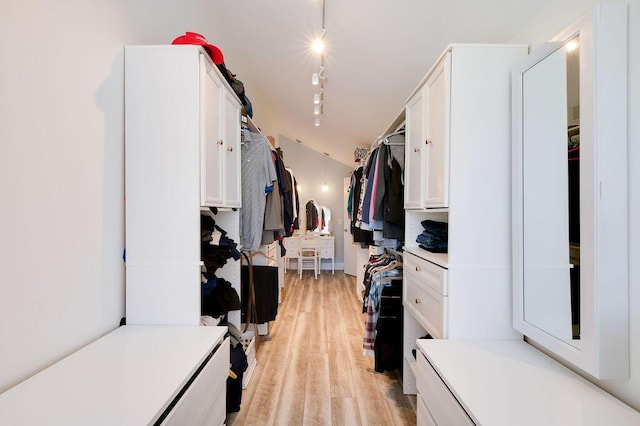 walk in closet with vaulted ceiling and light hardwood / wood-style flooring