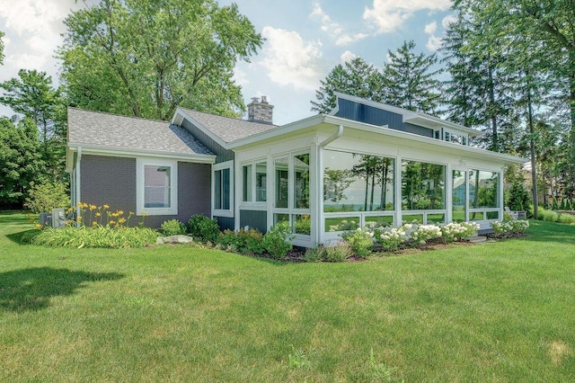 rear view of house with a sunroom and a lawn