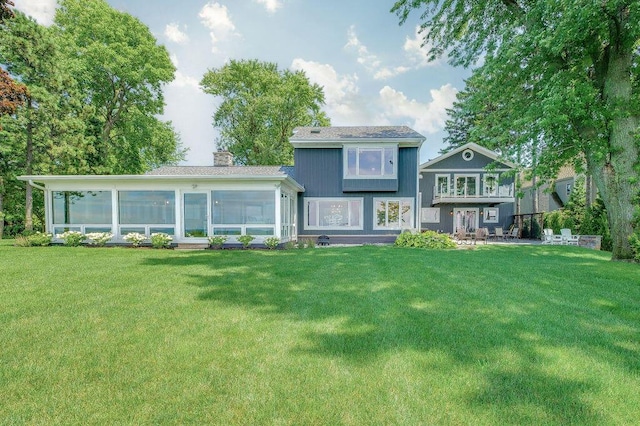 back of house with a sunroom and a lawn