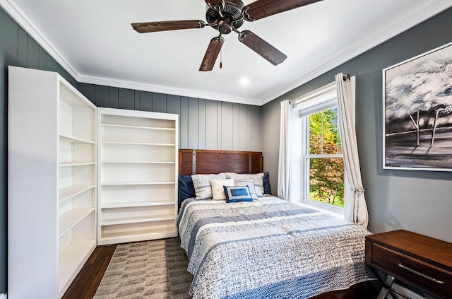 bedroom with crown molding, dark hardwood / wood-style floors, wooden walls, and ceiling fan