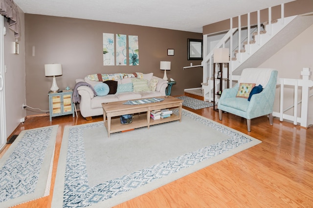 living room with stairs, wood finished floors, and baseboards