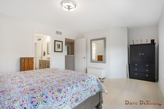 bedroom featuring connected bathroom and light hardwood / wood-style floors