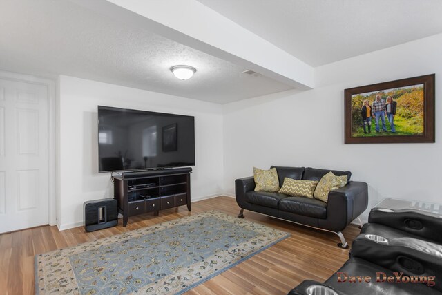 living room with beam ceiling, hardwood / wood-style flooring, and a textured ceiling