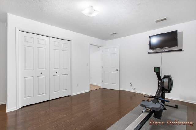 workout area with wood-type flooring and a textured ceiling