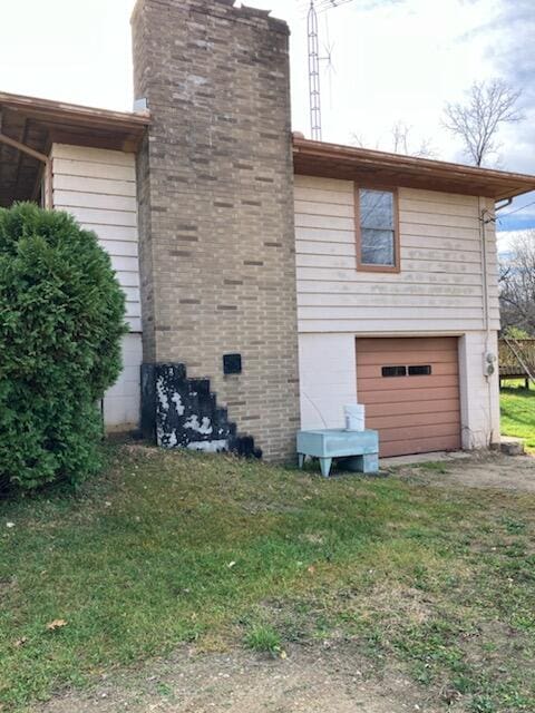 view of side of property with a garage and a lawn