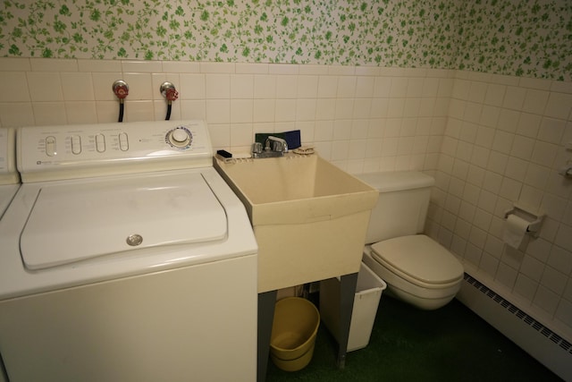 bathroom featuring sink, baseboard heating, tile walls, washer / dryer, and toilet