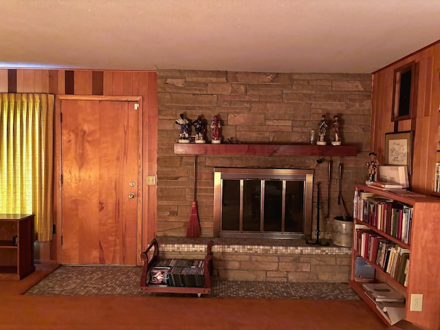 unfurnished living room featuring carpet flooring, a fireplace, and wood walls