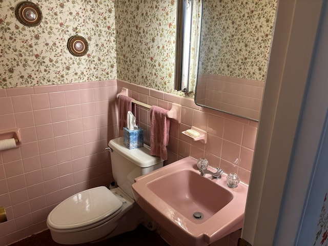 bathroom with tile walls, sink, and toilet