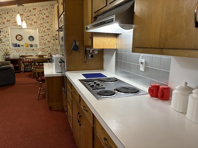 kitchen featuring tasteful backsplash, light carpet, black electric cooktop, and decorative light fixtures