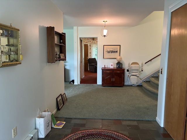 hall with a baseboard heating unit and dark colored carpet