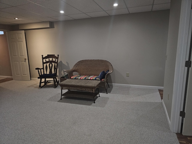 living area featuring carpet and a paneled ceiling