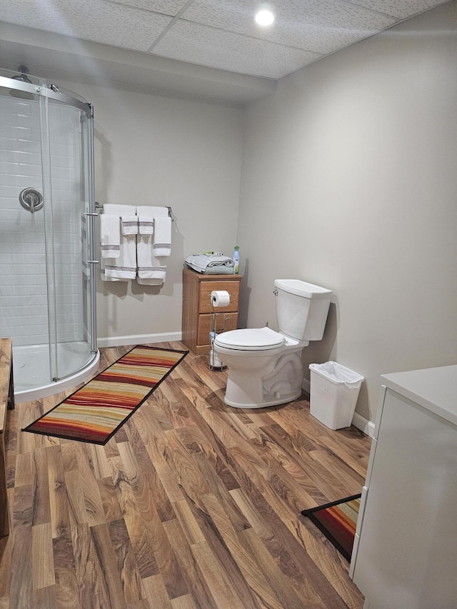 bathroom with hardwood / wood-style flooring, a paneled ceiling, toilet, and an enclosed shower