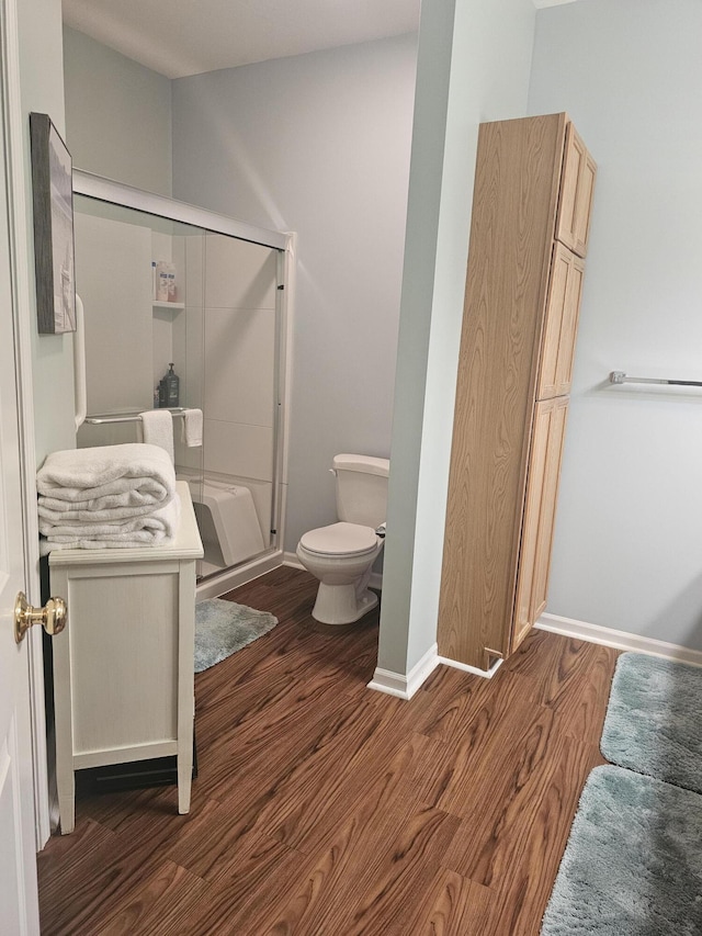 bathroom with an enclosed shower, vanity, wood-type flooring, and toilet