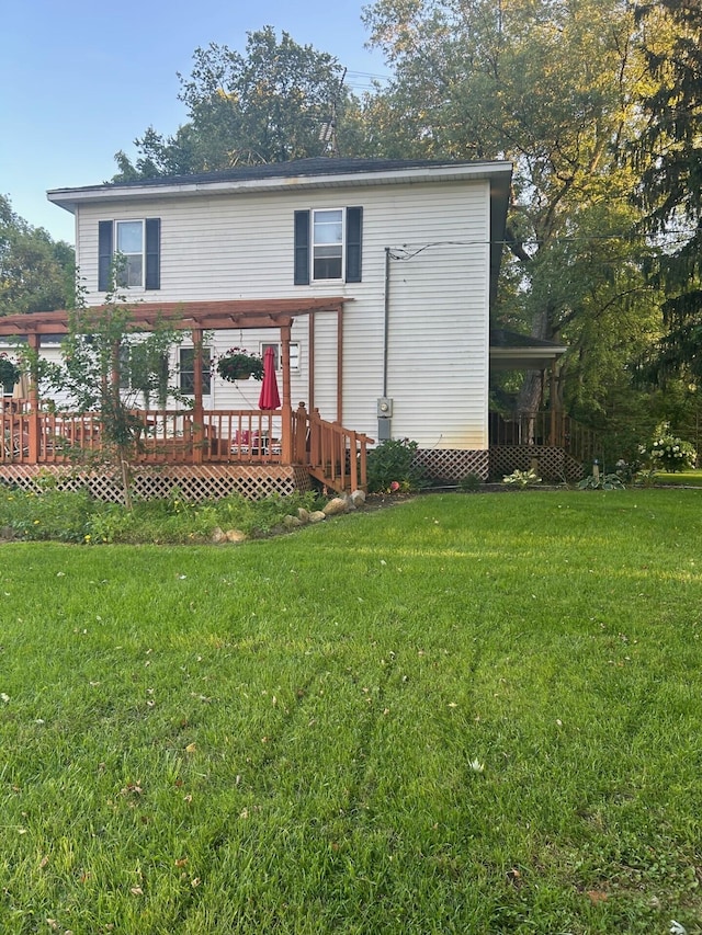 rear view of property featuring a lawn and a deck