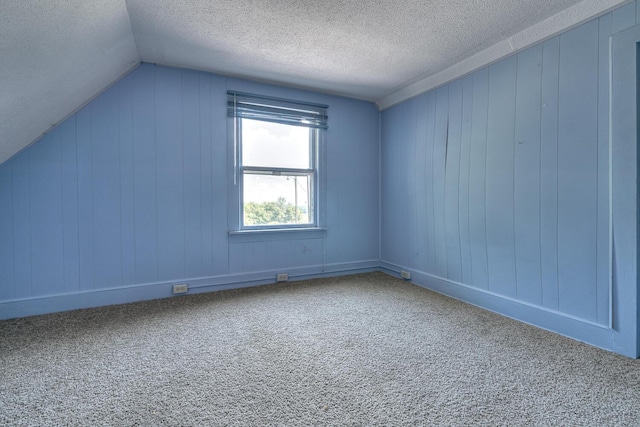 bonus room with lofted ceiling, carpet flooring, and a textured ceiling