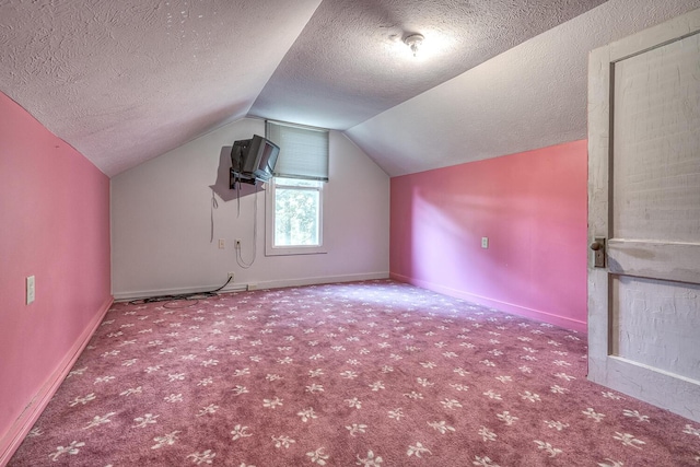 additional living space featuring carpet floors, vaulted ceiling, and a textured ceiling