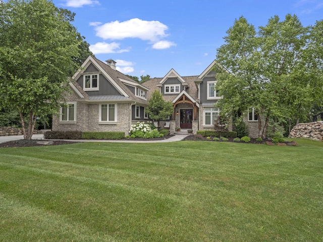 view of front facade featuring a standing seam roof, stone siding, a front yard, metal roof, and a chimney