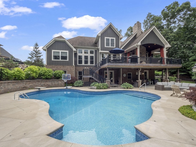 outdoor pool with an outdoor living space, stairway, a deck, a patio area, and a diving board