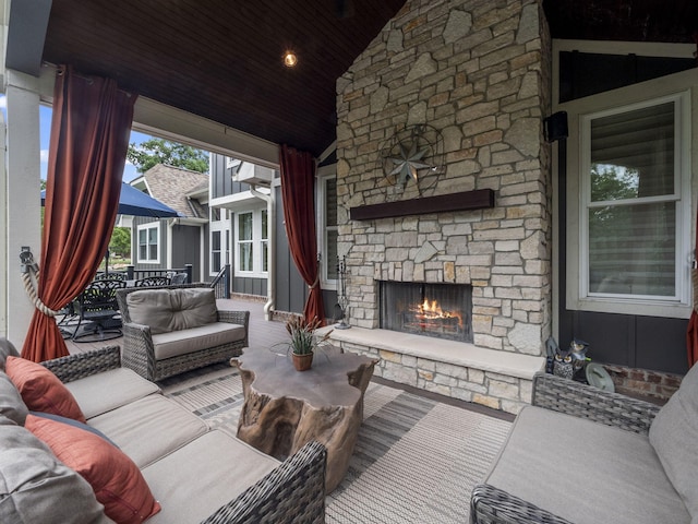 living area featuring high vaulted ceiling, an outdoor stone fireplace, and wooden ceiling