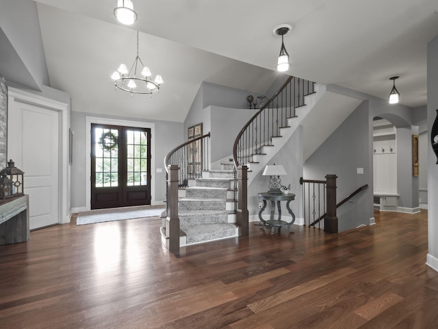 foyer with baseboards, french doors, wood finished floors, arched walkways, and a notable chandelier