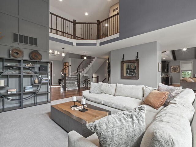 living area with stairway, wood finished floors, visible vents, recessed lighting, and a towering ceiling