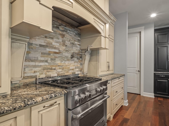 kitchen with dark wood-style floors, cream cabinets, and high end stainless steel range