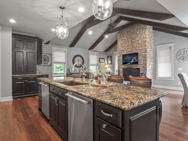 kitchen featuring dark wood-type flooring, a sink, dark stone countertops, dishwasher, and vaulted ceiling with beams