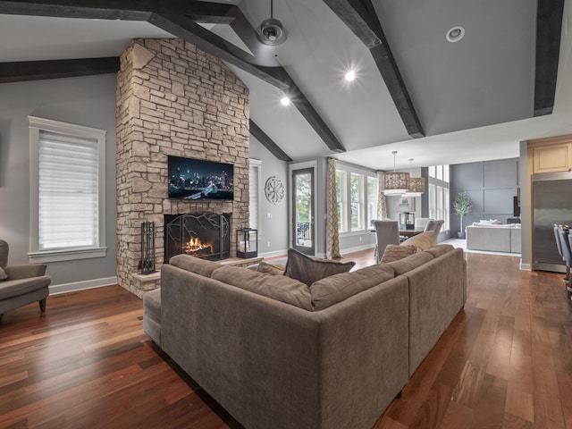 living area with beamed ceiling, baseboards, dark wood-type flooring, and a stone fireplace