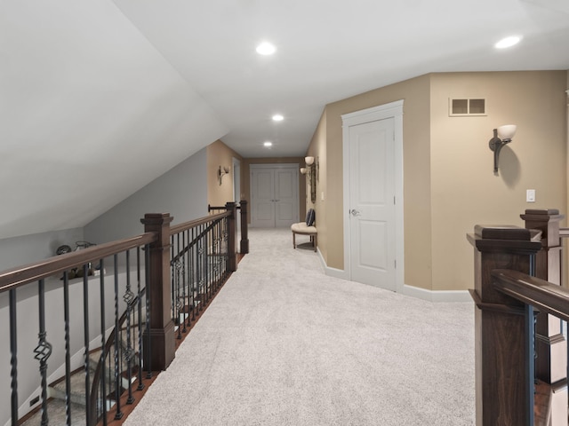 hallway featuring carpet, visible vents, baseboards, recessed lighting, and an upstairs landing