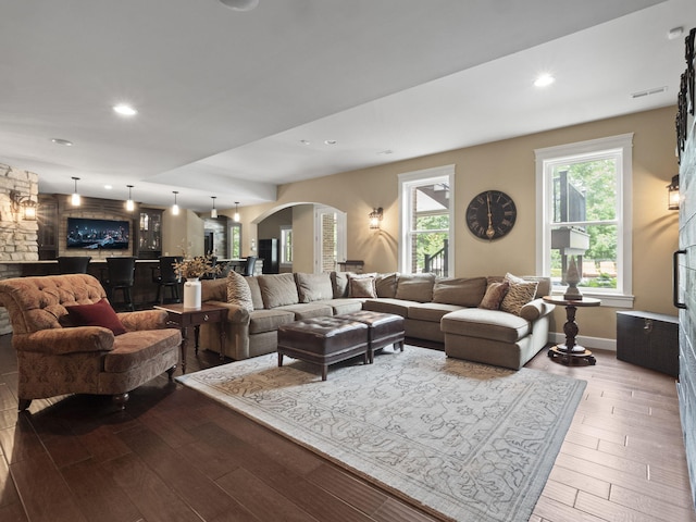 living room with recessed lighting, visible vents, arched walkways, and wood finished floors