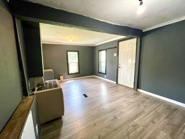 entrance foyer with a textured ceiling, light wood-type flooring, and crown molding