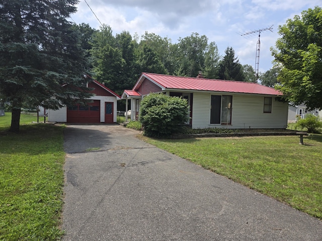 view of front of house featuring a garage, an outdoor structure, and a front lawn