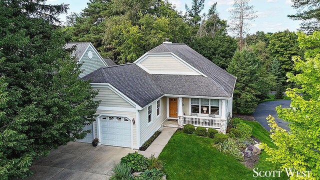 view of front of home with covered porch, a garage, and a front yard