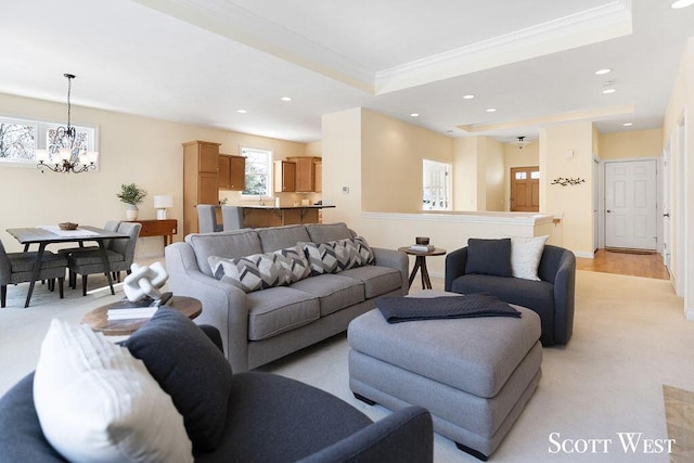 living area featuring a tray ceiling, recessed lighting, an inviting chandelier, ornamental molding, and baseboards