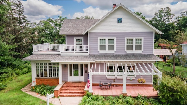 view of front of house with a balcony, a wooden deck, and a front yard