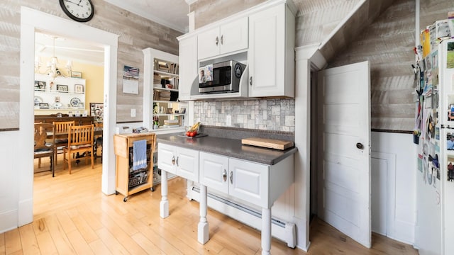 kitchen with backsplash, light wood-type flooring, ornamental molding, white cabinets, and baseboard heating