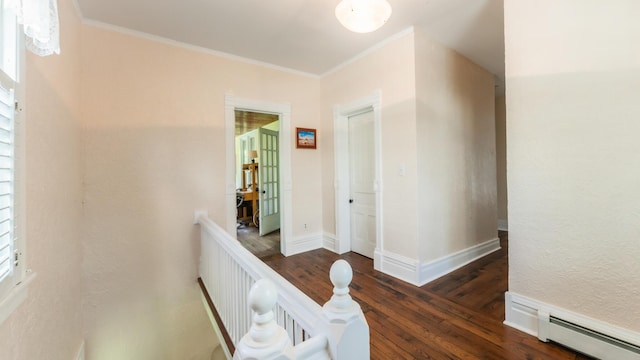 corridor with a baseboard heating unit, dark hardwood / wood-style floors, and ornamental molding