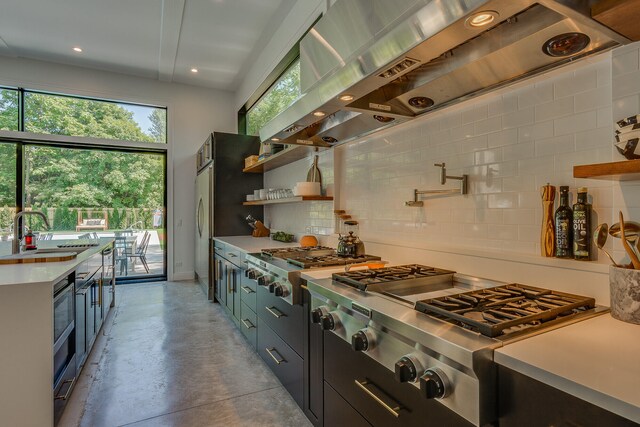15963 Lakeshore Rd, Union Pier, MI 49129 - kitchen featuring tasteful backsplash, wall chimney exhaust hood, a sink, light countertops, and finished concrete flooring