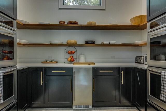 15963 Lakeshore Rd, Union Pier, MI 49129 - kitchen featuring light countertops, appliances with stainless steel finishes, open shelves, and dark cabinetry