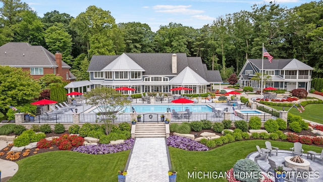 rear view of house with a community pool, a yard, a patio, and an outdoor fire pit