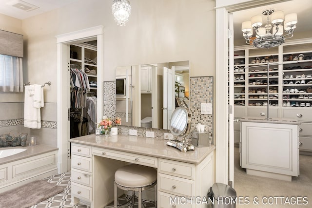 bathroom featuring tasteful backsplash, vanity, a chandelier, and a washtub