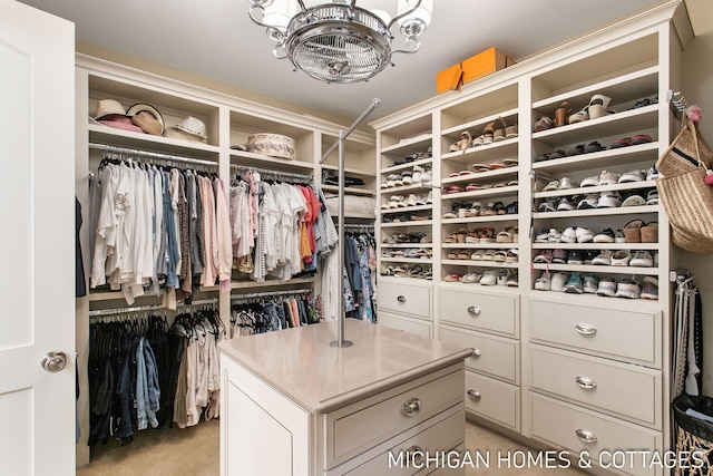 walk in closet featuring light colored carpet and a chandelier